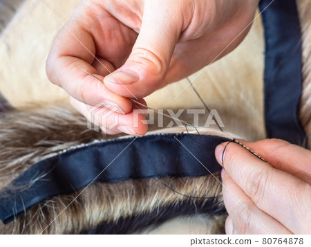 furrier stitches fur pelts by needle close up 80764878