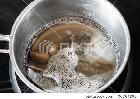 silver cutlery in boiling solution of baking soda 80764896