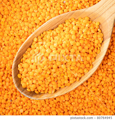 whole red lentils in wooden spoon closeup 80764945