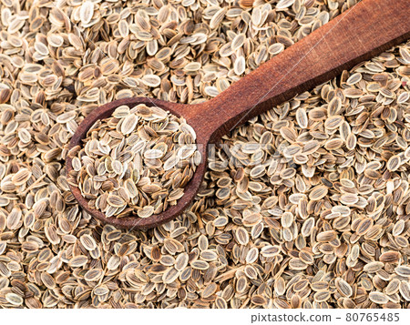 wood spoon on pile of dill seeds closeup 80765485
