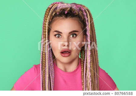 surprised woman with dreadlocks on green background. 80766588