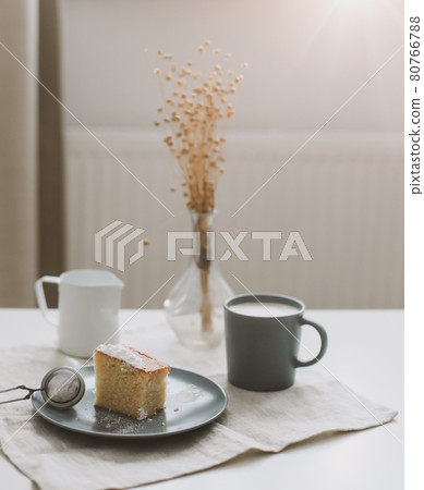 Morning breakfast with a piece of fresh homemade cake with a cup of cappuccino on a table with linen tablecloth. Morning breakfast with a piece of fresh homemade cake with a cup of cappuccino on a table with linen tablecloth. 80766788