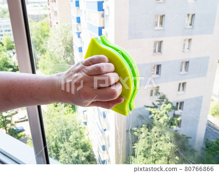 hand with double-sided cleaner cleans window 80766866