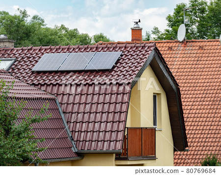 Electric solar panels on the tiled roof of family house. The insulated facade Electric solar panels on the tiled roof of family house. The insulated facade 80769684