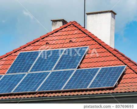 Solar panels installed on the red tiled roof of a house  Europe. 80769693