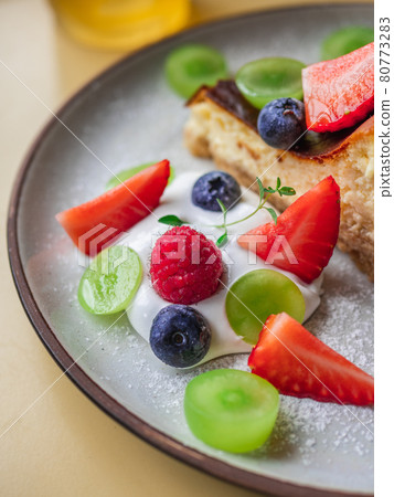 Close-up shot of mixed berries and whipped cream in a plate of cheesecake. Close-up shot of mixed berries and whipped cream in a plate of cheesecake. 80773283