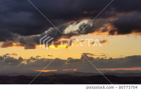 Sunset over the mountains and valleys of the Apennines with large colored clouds laden with rain Sunset over the mountains and valleys of the Apennines with large colored clouds laden with rain 80773704