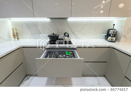 Open drawer with cutlery at modern white woden kitchen in classic style 80774857