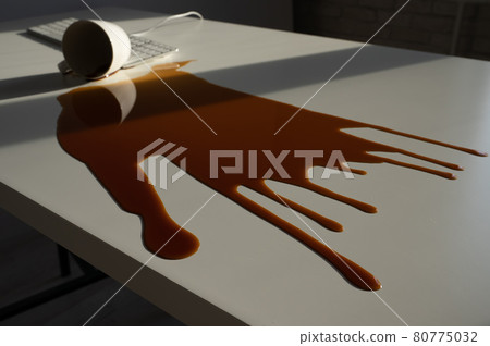 Spilled cup of black coffee on computer keyboard on white table. 80775032