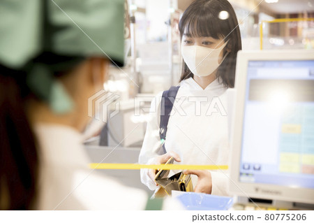 A woman in a mask who pays at a supermarket cashier who has taken measures against infection 80775206