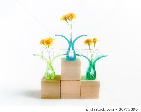 Yellow flowers sandwiched between plastic clips standing on the podium of a wooden block Yellow flowers sandwiched between plastic clips standing on the podium of a wooden block 80775896