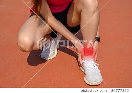 Cropped shot of woman runner kneel down, suffering from ankle pain. Ankle pain may be caused by an injury, like a sprain, or by a medical condition, such as arthritis. 80777223