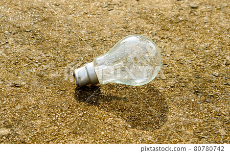 One transparent fluorescent Light bulb in the sunlight with shadow on the floor. Renewable energy technology ecology background. One transparent fluorescent Light bulb in the sunlight with shadow on the floor. Renewable energy technology ecology background. 80780742