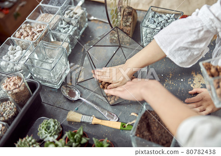 caucasian confident happy florist is working with composition made from glass stones and plants in botanic shop caucasian confident happy florist is working with composition made from glass stones and plants in botanic shop 80782438