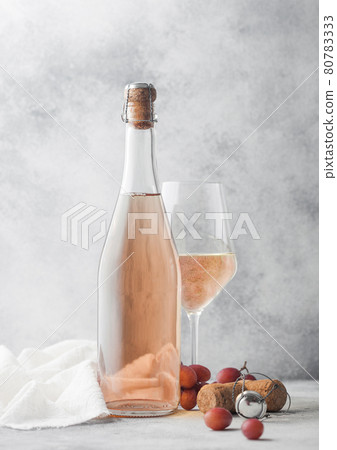 Bottle and glass of pink rose homemade wine with grapes and corkscrew with linen cloth on light background. Bottle and glass of pink rose homemade wine with grapes and corkscrew with linen cloth on light background. 80783333