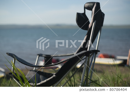 Camping folding chair against the backdrop of the lake. Camping folding chair against the backdrop of the lake. 80786404
