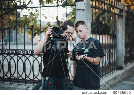 Work of professional filming crew, young operator looks on a screen  80786600