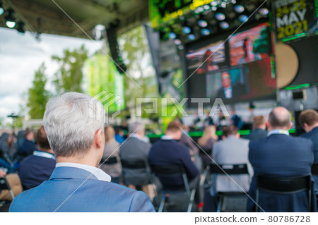 Participants of open air conference listening to speaker 80786728