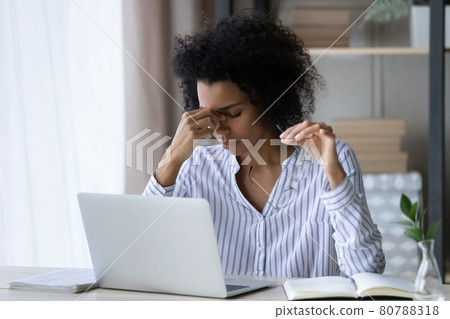 Unhealthy ethnic woman suffer from migraine at computer Unhealthy ethnic woman suffer from migraine at computer 80788318