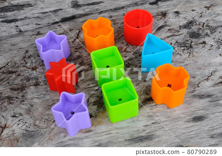 Isolated children's toy blocks in various shapes made of plastic on wood grain background.  80790289