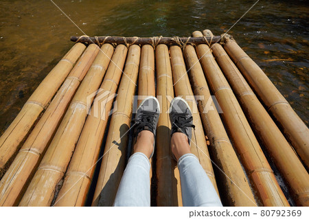Woman sitting on the bamboo raft floating in clear water Woman sitting on the bamboo raft floating in clear water 80792369