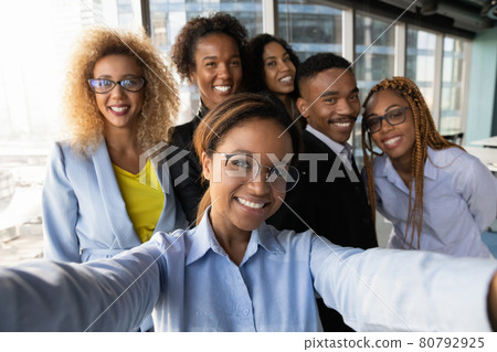 Smiling african woman making selfie with motivated colleagues. 80792925