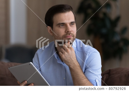 Thoughtful young businessman using tablet computer looking aside having idea 80792926