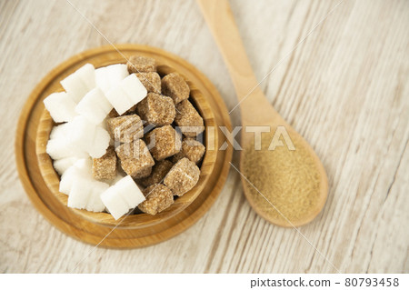 Brown sugar in a square cup and wooden spoon on a wooden table, healthy sugar is used for cooking food or desserts. Brown sugar in a square cup and wooden spoon on a wooden table, healthy sugar is used for cooking food or desserts. 80793458