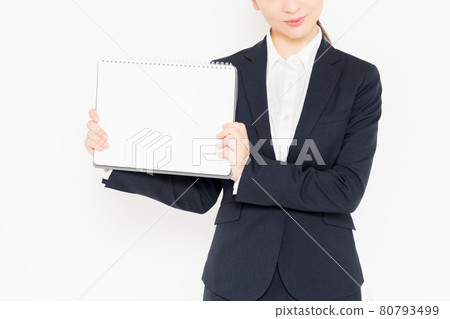 Businesswoman in a suit with a small sketchbook standing in front of a white background Businesswoman in a suit with a small sketchbook standing in front of a white background 80793499