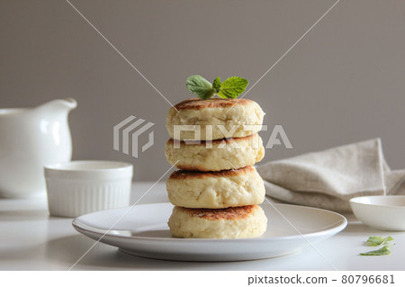 Sweet cheese pancakes with honey on a white plate. Homemade recipe cheesecakes. Sweet cheese pancakes with honey on a white plate. Homemade recipe cheesecakes. 80796681