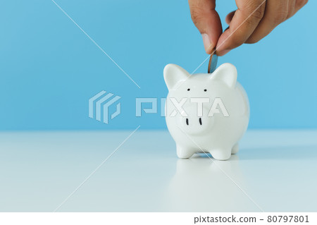 White piggy bank with hand putting money coins on blue background, copy space. 80797801