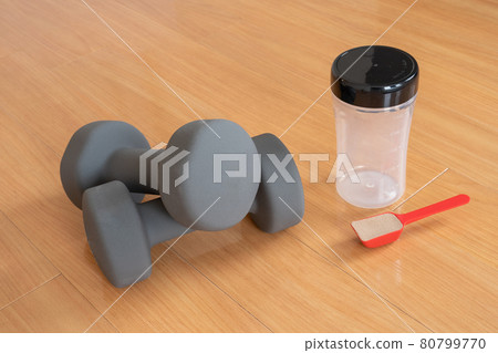 Two gray dumbbells and a shaker and a spoon with protein Two gray dumbbells and a shaker and a spoon with protein 80799770