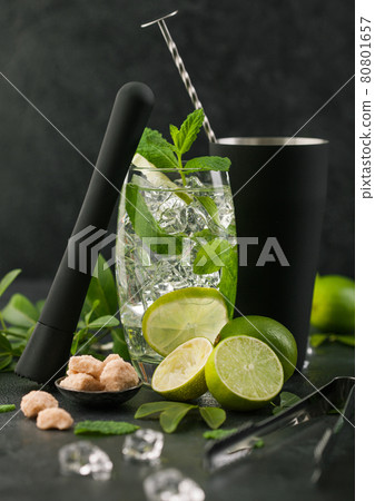 Glass of Mojito cocktail with ice cubes mint and lime on black board with spoon in shake  80801657