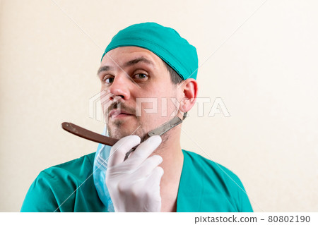 Funny doctor with a straight razor in his hands. 80802190