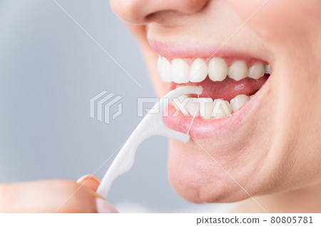 Caucasian woman brushing teeth with toothpick with dental floss on white background. Caucasian woman brushing teeth with toothpick with dental floss on white background. 80805781