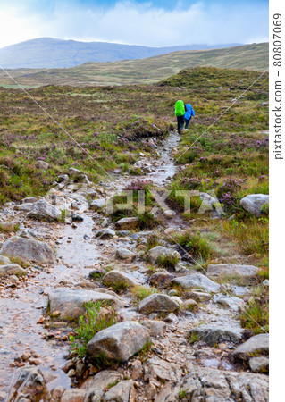 Couple hiking along a trail on a rainy day 80807069