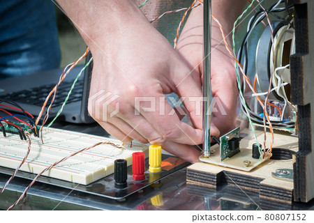 Hands connect electronic contacts of homemade radio. Hobby of making retro things. Hands connect electronic contacts of homemade radio. Hobby of making retro things. 80807152