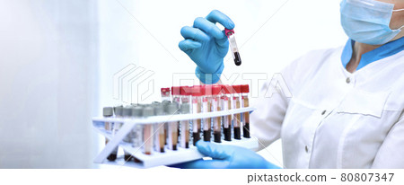 Hands of the laboratory assistant while working with blood tests in test tubes. Hands of the laboratory assistant while working with blood tests in test tubes. 80807347