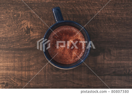 Closeup of hot cocoa drink in blue mug on wooden table. 80807380