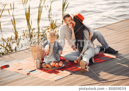 Family with little daughter sitting near water in a autumn park 80809039