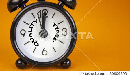 Quality time symbol. Beautiful black alarm clock with words 'quality time'. Beautiful orange background. Copy space. Business and quality time concept. Quality time symbol. Beautiful black alarm clock with words 'quality time'. Beautiful orange background. Copy space. Business and quality time concept. 80809203
