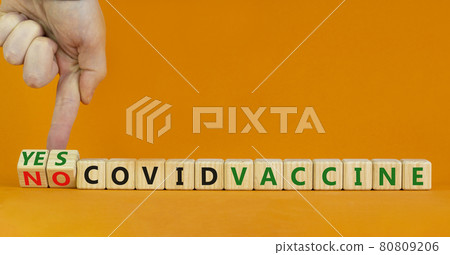 Covid vaccine yes or no symbol. Doctor turns cubes and changes words 'covid vaccine no' to 'covid vaccine yes'. Beautiful orange background, copy space. Covid-19 vaccine and medical concept. Covid vaccine yes or no symbol. Doctor turns cubes and changes words 'covid vaccine no' to 'covid vaccine yes'. Beautiful orange background, copy space. Covid-19 vaccine and medical concept. 80809206
