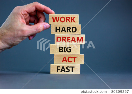 Work hard dream big symbol. Words 'Work hard dream big act fast' on wooden blocks on a beautiful grey background. Businessman hand. Business, motivational and work hard dream big act fast concept. Work hard dream big symbol. Words 'Work hard dream big act fast' on wooden blocks on a beautiful grey background. Businessman hand. Business, motivational and work hard dream big act fast concept. 80809267