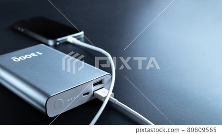 Phone power bank. Mobile phone or smartphone battery charging from portable powerbank with white usb cable. External battery for mobile devices. Phone power bank. Mobile phone or smartphone battery charging from portable powerbank with white usb cable. External battery for mobile devices. 80809565