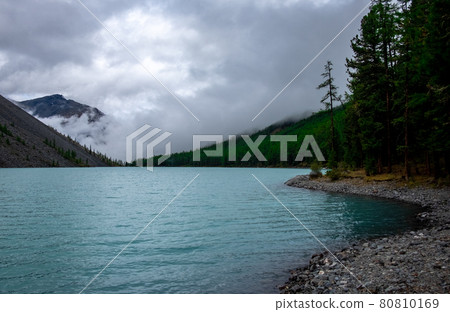 Shavlinskoye lake in the Altai Republic on the background of mountain peaks shrouded in fog. Shavlinskoye lake in the Altai Republic on the background of mountain peaks shrouded in fog. 80810169