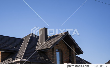 Brown corrugated metal profile roof installed on a modern house. The roof of corrugated sheet. Roofing of metal profile wavy shape. Modern roof made of metal. Metal roofing. Brown corrugated metal profile roof installed on a modern house. The roof of corrugated sheet. Roofing of metal profile wavy shape. Modern roof made of metal. Metal roofing. 80810397