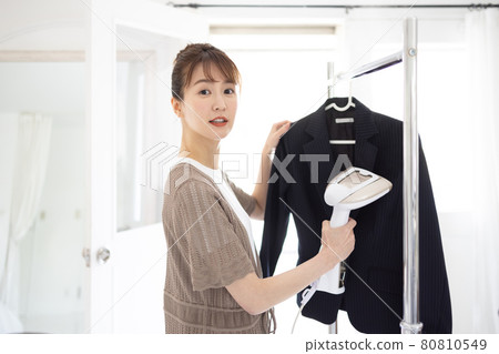 Young woman ironing a jacket Young woman ironing a jacket 80810549