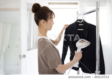 Young woman ironing a jacket 80810552