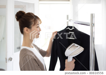 Young woman ironing a jacket Young woman ironing a jacket 80810556