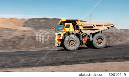 Large quarry dump truck. Big yellow mining truck at work site. Loading coal into body truck. Production useful minerals. Mining truck mining machinery to transport coal from open-pit production Large quarry dump truck. Big yellow mining truck at work site. Loading coal into body truck. Production useful minerals. Mining truck mining machinery to transport coal from open-pit production 80810649